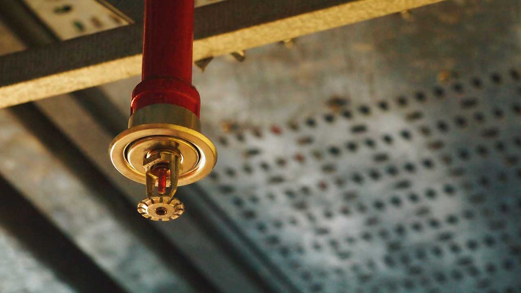 Элемент системы пенного пожаротушения: спринклерный ороситель на фоне потолка